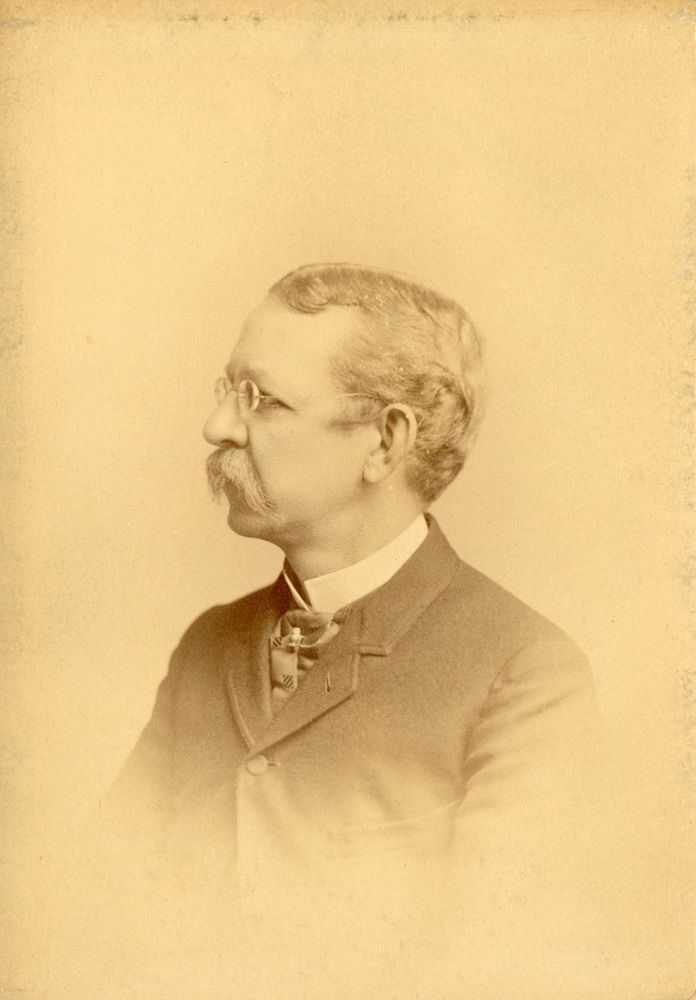 A yellowed side portrait of Francis Anthony Drexel. He is facing to the left and is wearing circular glasses and has a thick mustache.