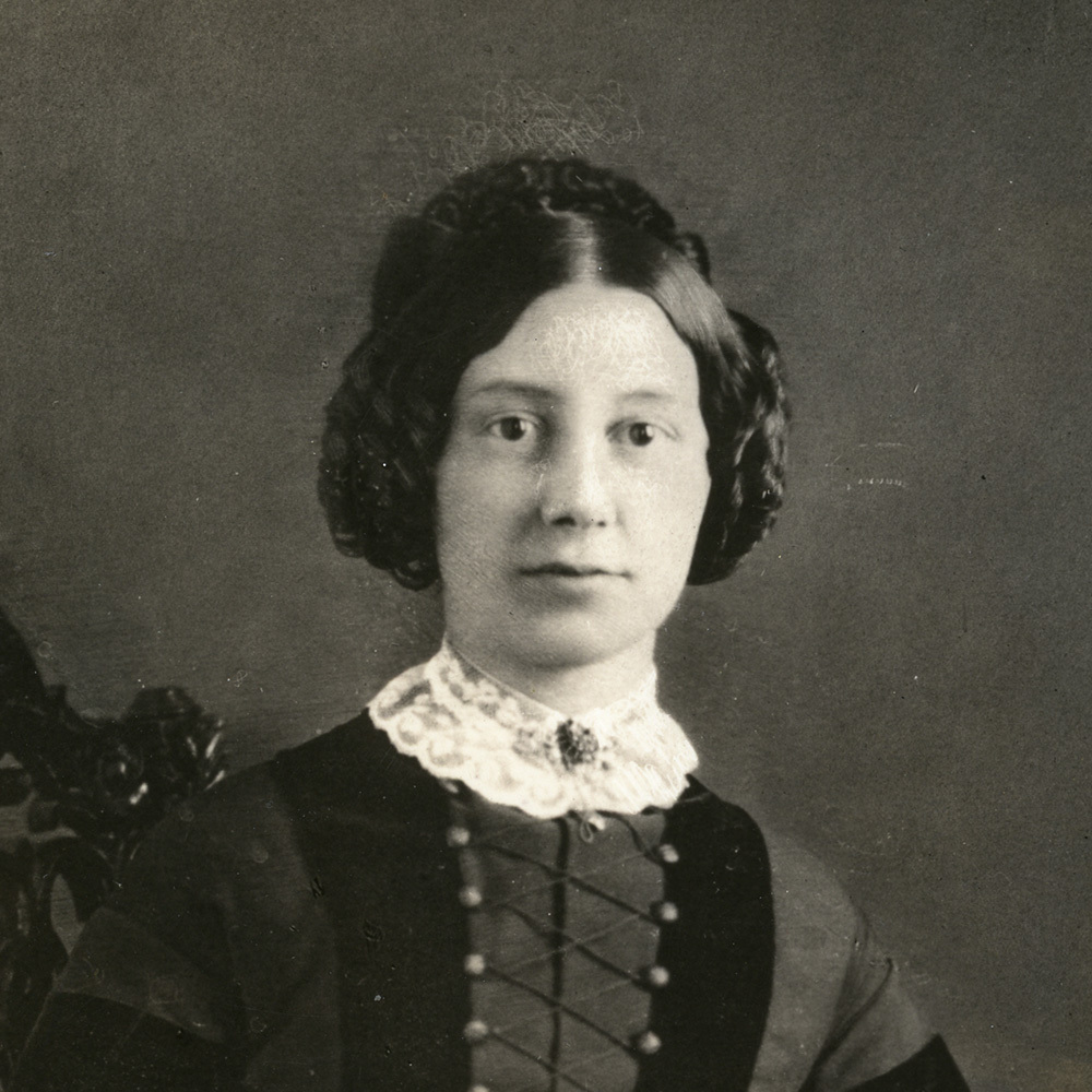 A black and white photograph of Hanna Jane Langstroth Drexel. She is wearing a dark long-sleeved dress with a white lace collar and her dark hair is curled and pinned up.