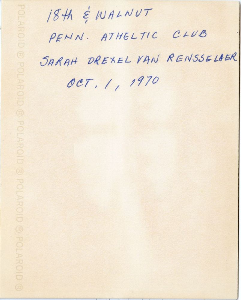 The yellowed back of a Polaroid photo with blue writing.