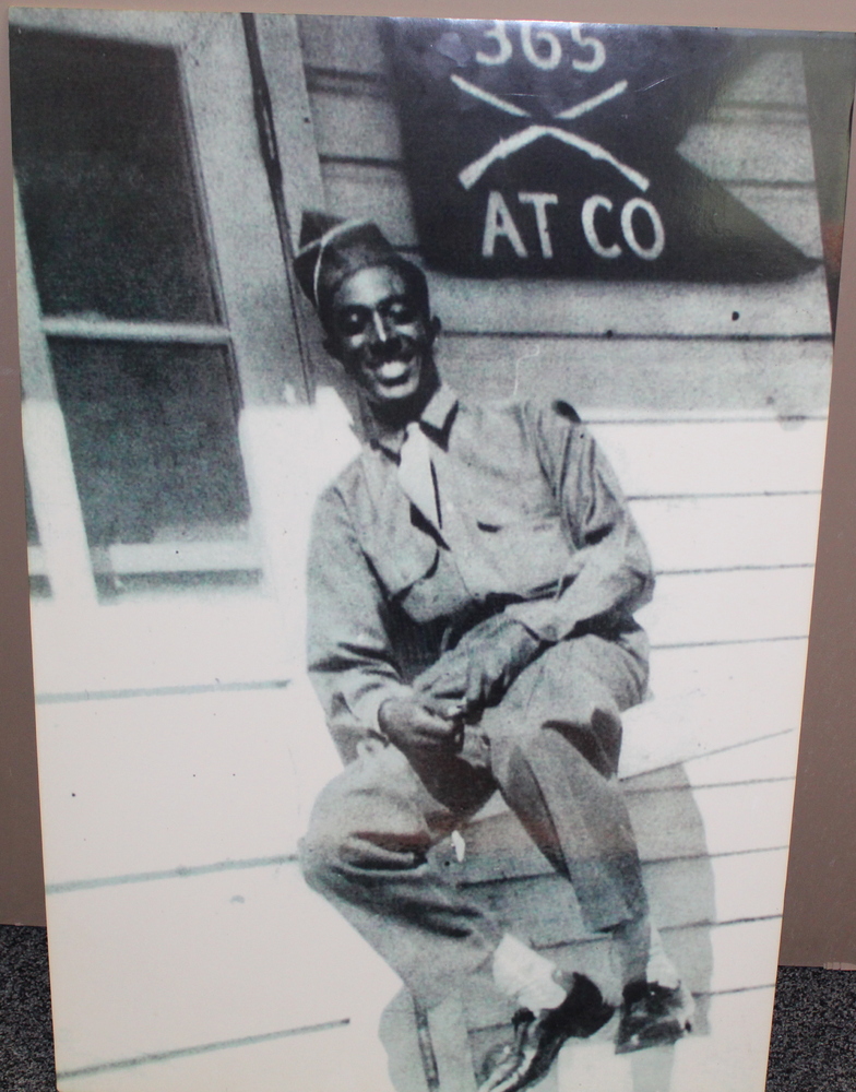 A slightly out of focus William Chase in his 92nd Infantry uniform in front of a building.
