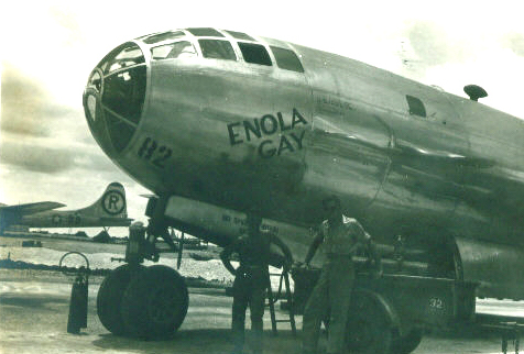 Damaged photograph of two men standing under the Enola Gay.