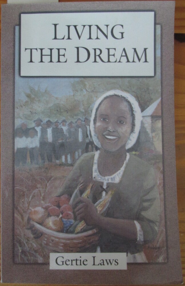 This book is titled "Living the Dream" by Gertie Laws. The cover of the book includes an illustration of a young woman in period clothing carrying a basket of vegetables. There is a field and crowd gathered behind her.